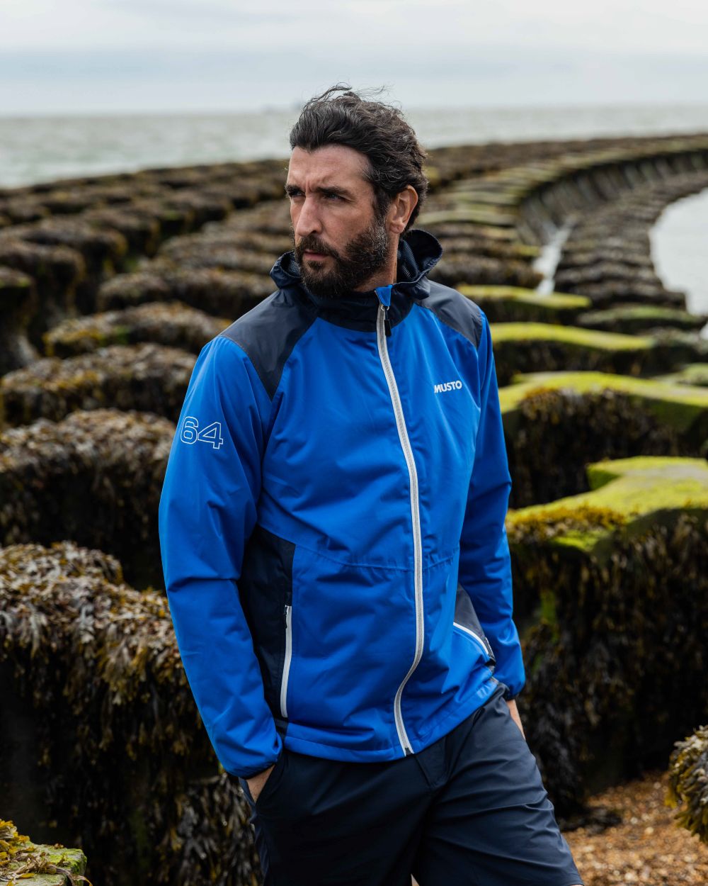 Navy Coloured Musto Mens RIB Fast Dry Shorts On A Coastal Background