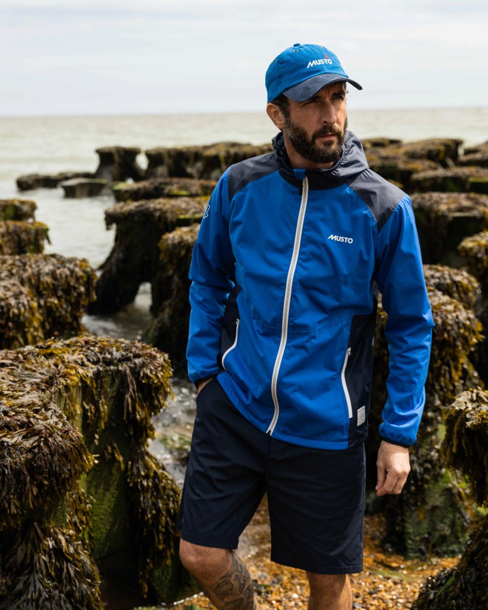 Navy Coloured Musto Mens RIB Fast Dry Shorts On A Coastal Background
