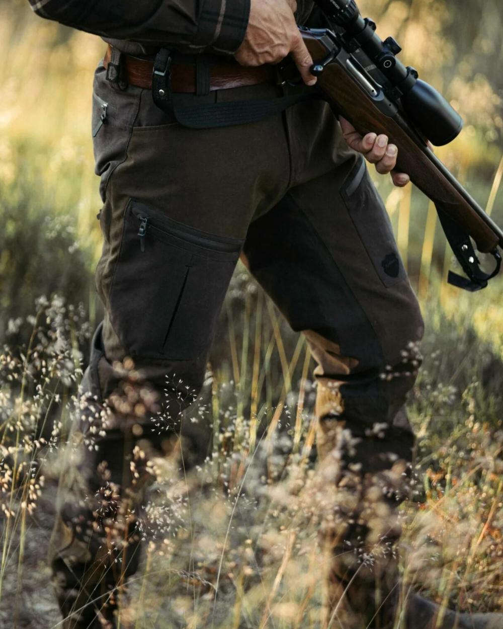 Green coloured Northern Hunting Mens Hakan Bark Waterproof Hunting Trousers on forest background