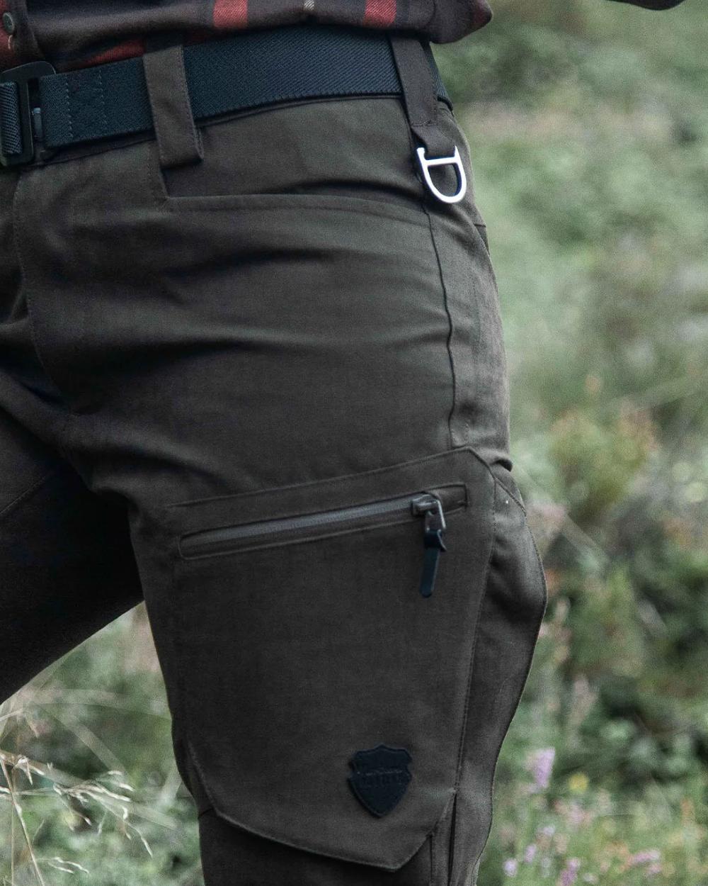 Dark Green coloured Northern Hunting Womens Alva Una G2 Hunting Trousers on forest background
