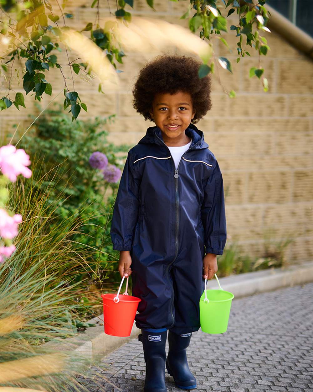 Navy coloured Regatta Kids Breathable Paddle Rain Suit with plants in background