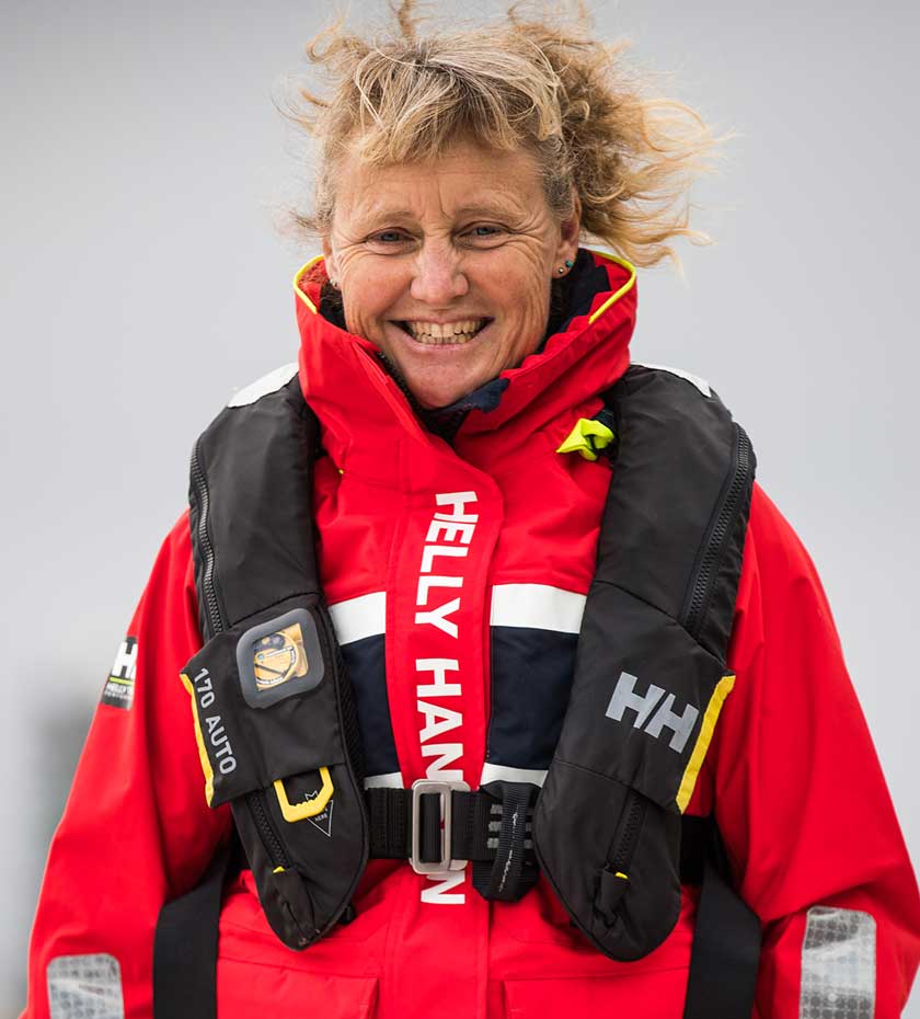 Life Jackets - Woman wears a black Helly Hansen life preserver vest over a red sailing jacket.