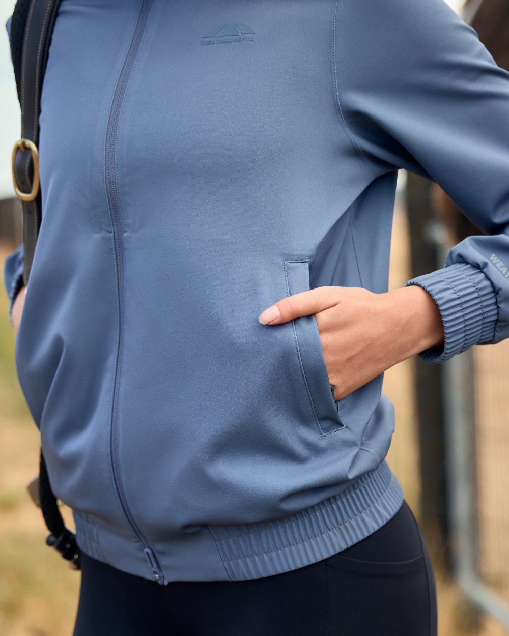 Slate Blue coloured WeatherBeeta Womens Waterproof Team Jacket on outdoor background