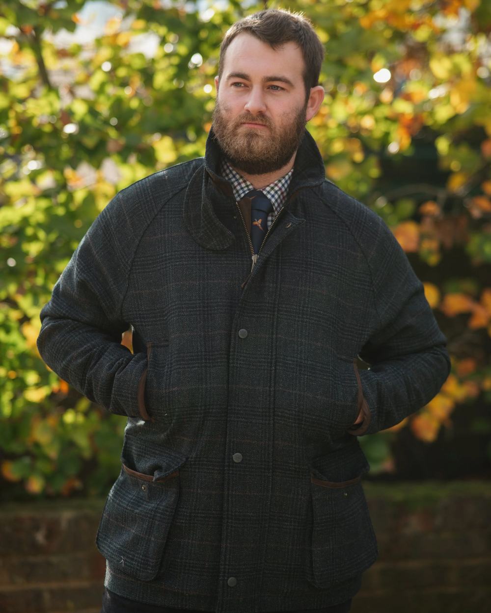 Green Check Coloured Alan Paine Surrey Waterproof Tweed Coat On A Leafy Background