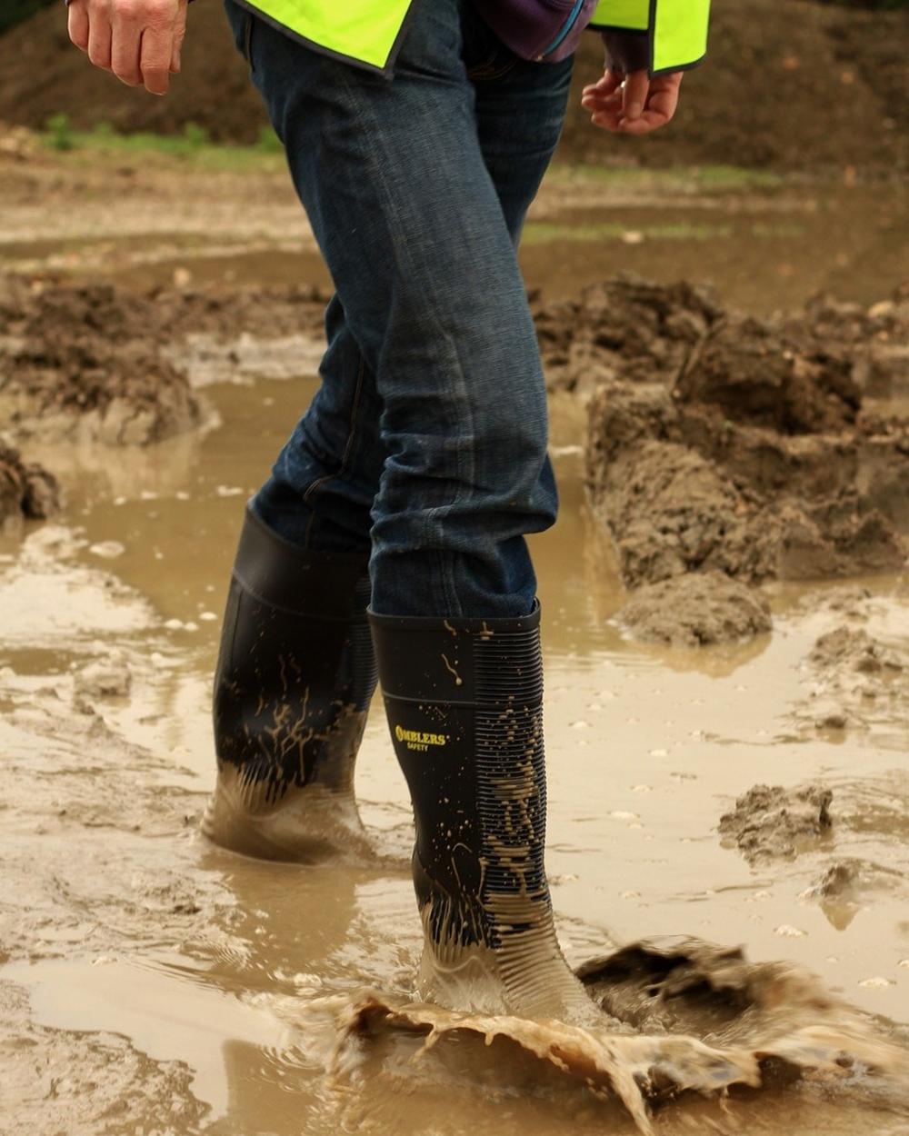 Black Coloured Amblers Safety FS100 Construction Safety Wellington on a muddy background