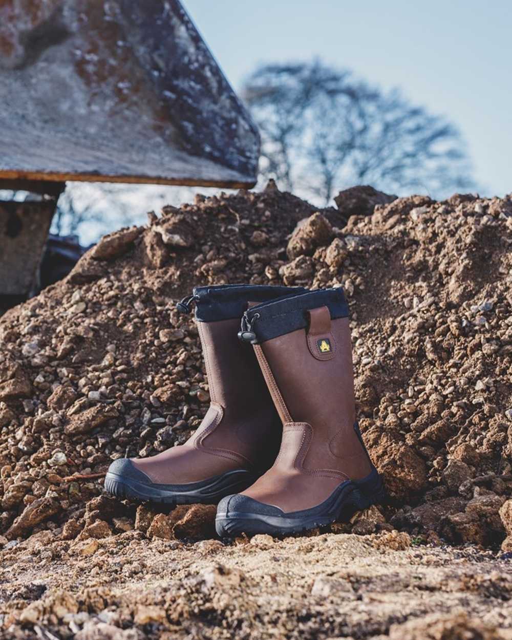 Brown Coloured Amblers Safety FS245 Antistatic Pull On Safety Rigger Boots on a muddy background