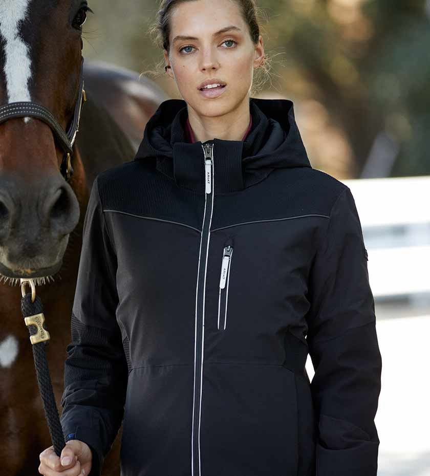 Woman with horse wears a black Ariat riding jacket.