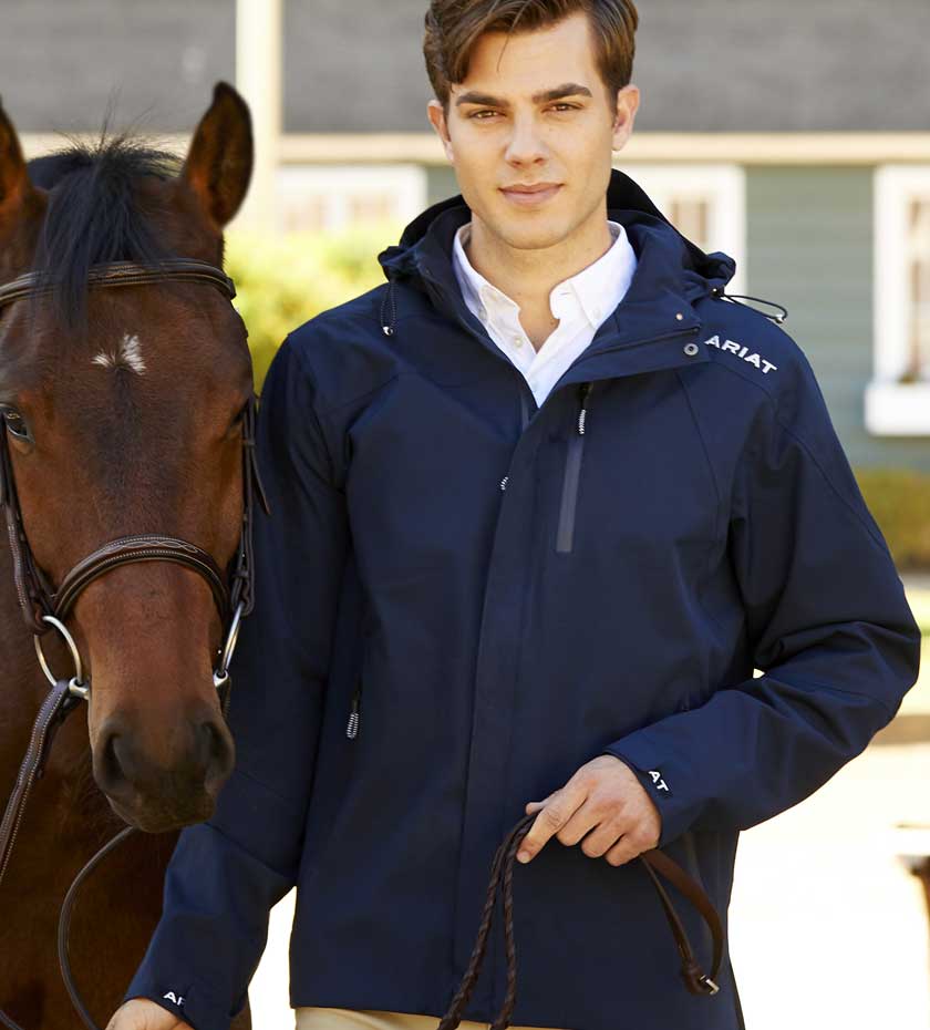 Man with horse wearing navy blue Ariat equestrian jacket.