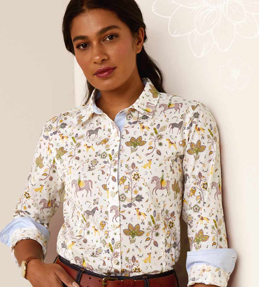 Woman wears Ariat flora long sleeve shirt in beige blue and gold.
