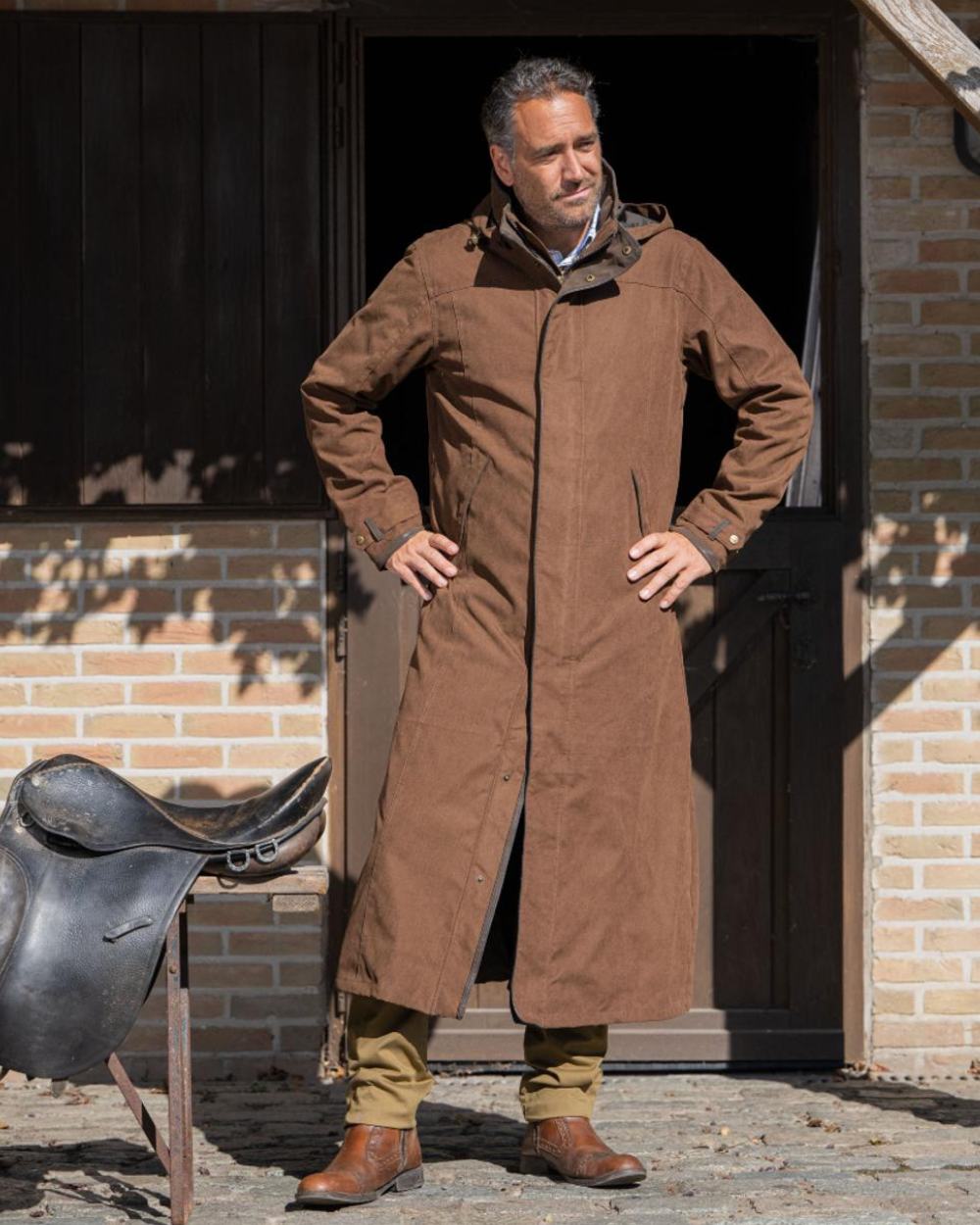 Earth Brown Coloured Baleno Livingstone Long Waterproof Coat On A Backyard Background