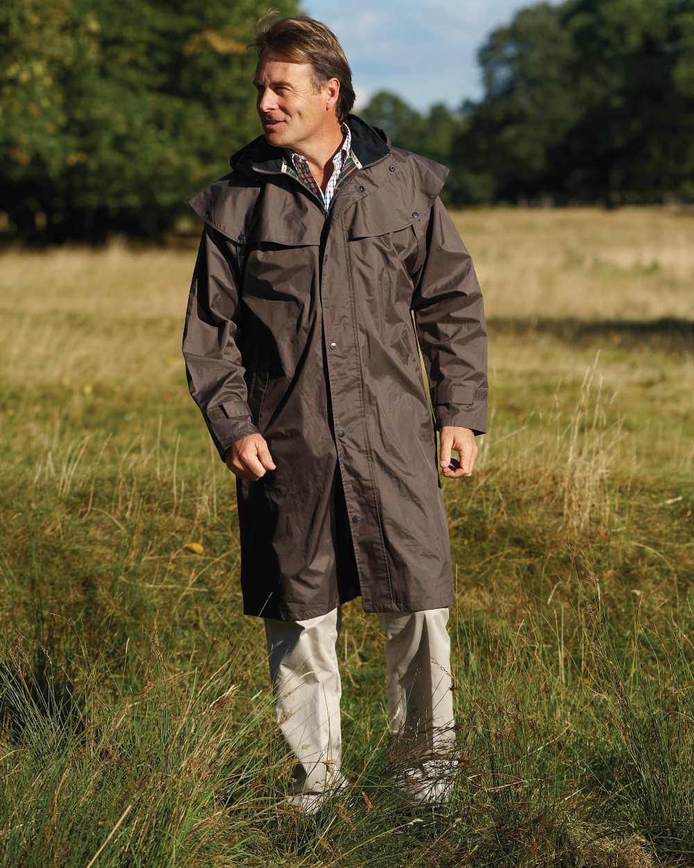 Brown Coloured Champion Highgrove Long Waterproof Coat On A Field Background