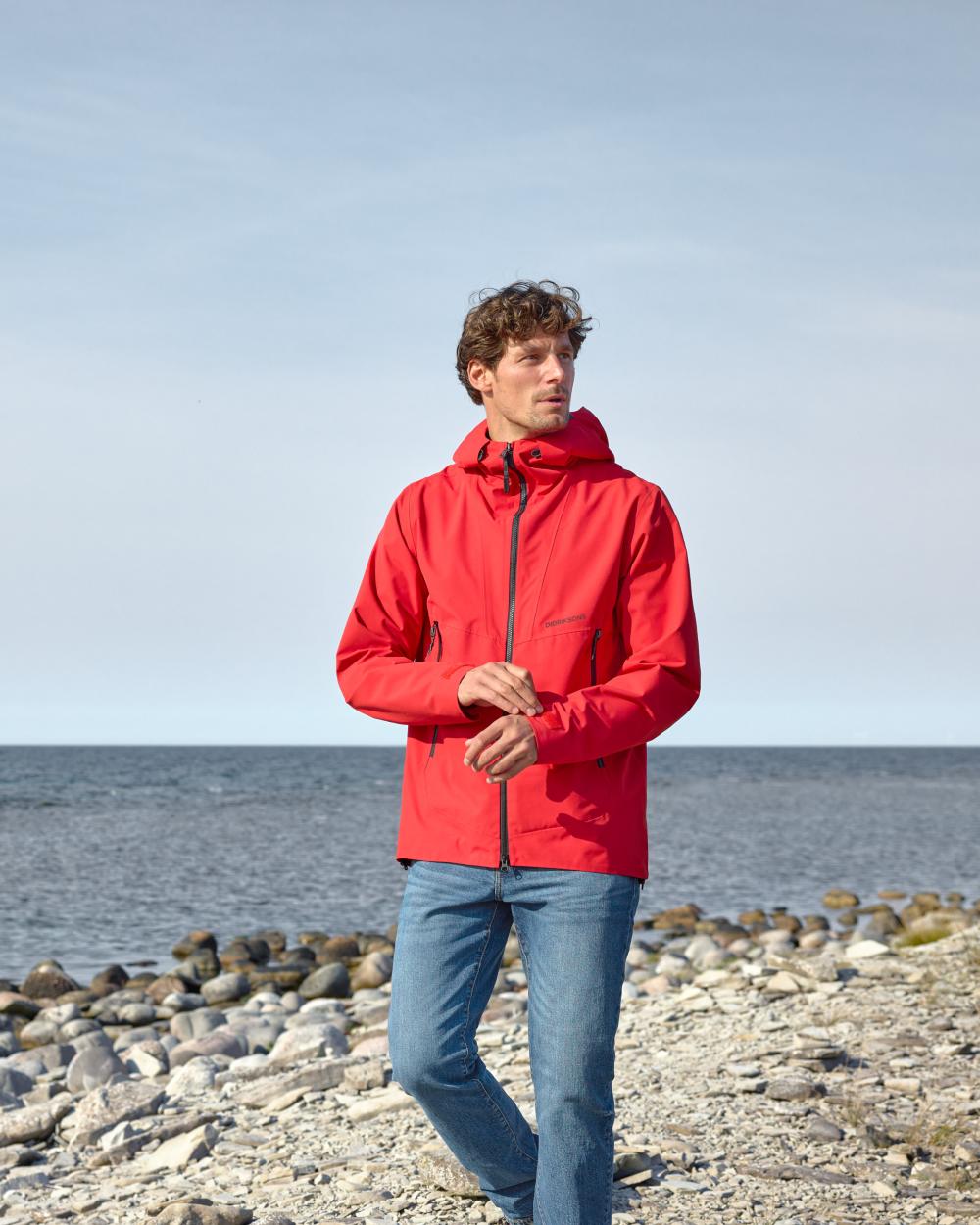 Pomme Red Coloured Didriksons Basil Unisex Waterproof Jacket 4 on Beach Background
