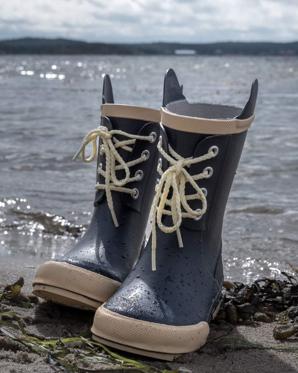 Navy Coloured Didriksons Childrens Splashman Boots On A Coastal Background