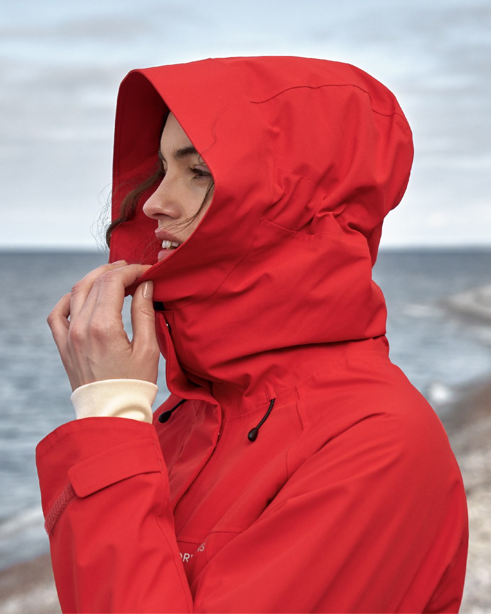 Pomme Red coloured Didriksons Womens Parka on beach background