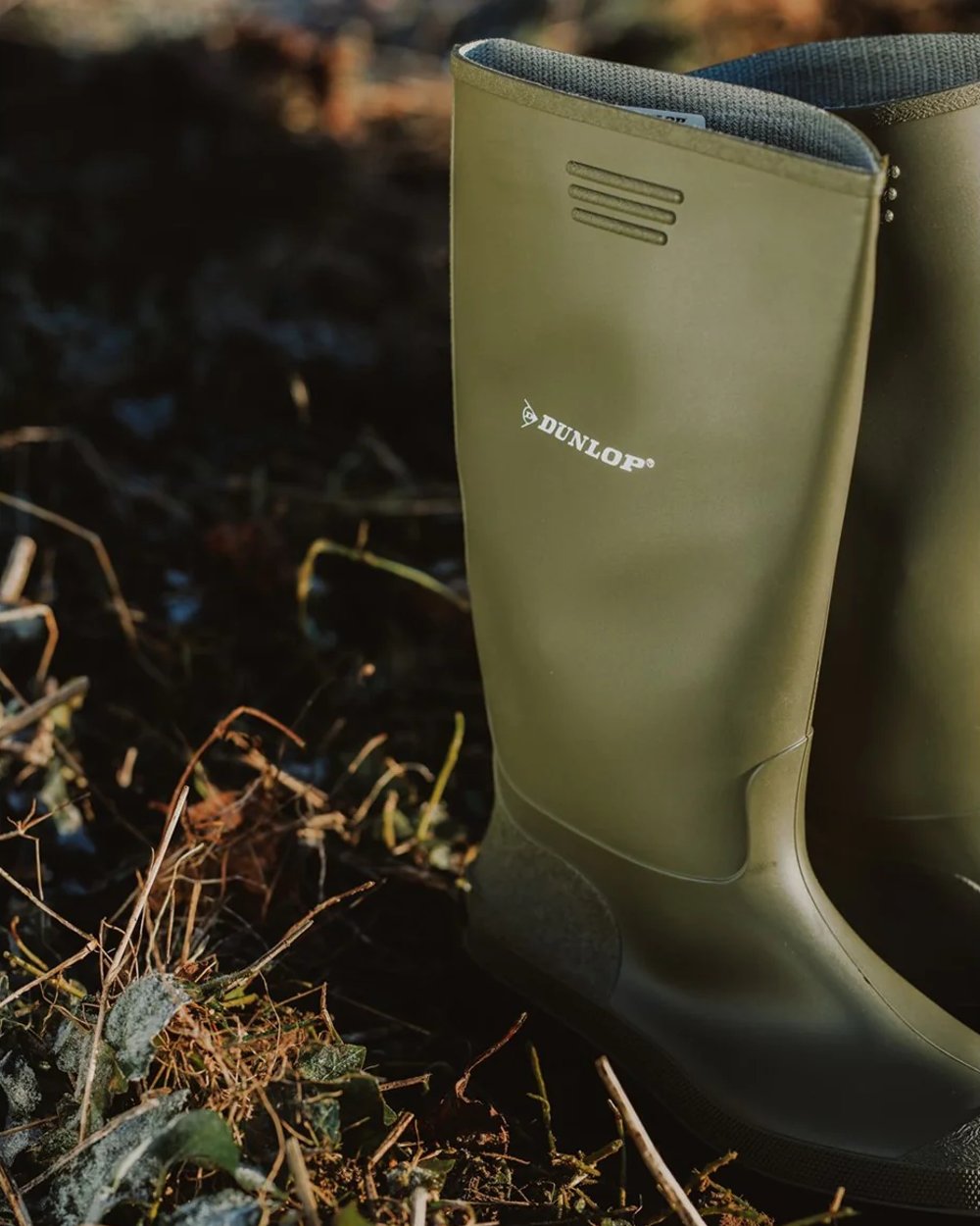 Green coloured Dunlop Pricemastor Wellingtons on blurry background