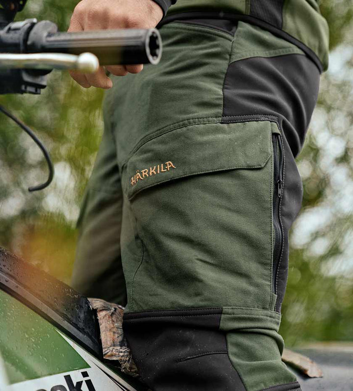Harkila hunting trousers in green with HARKILA gold logo on cargo pocket.