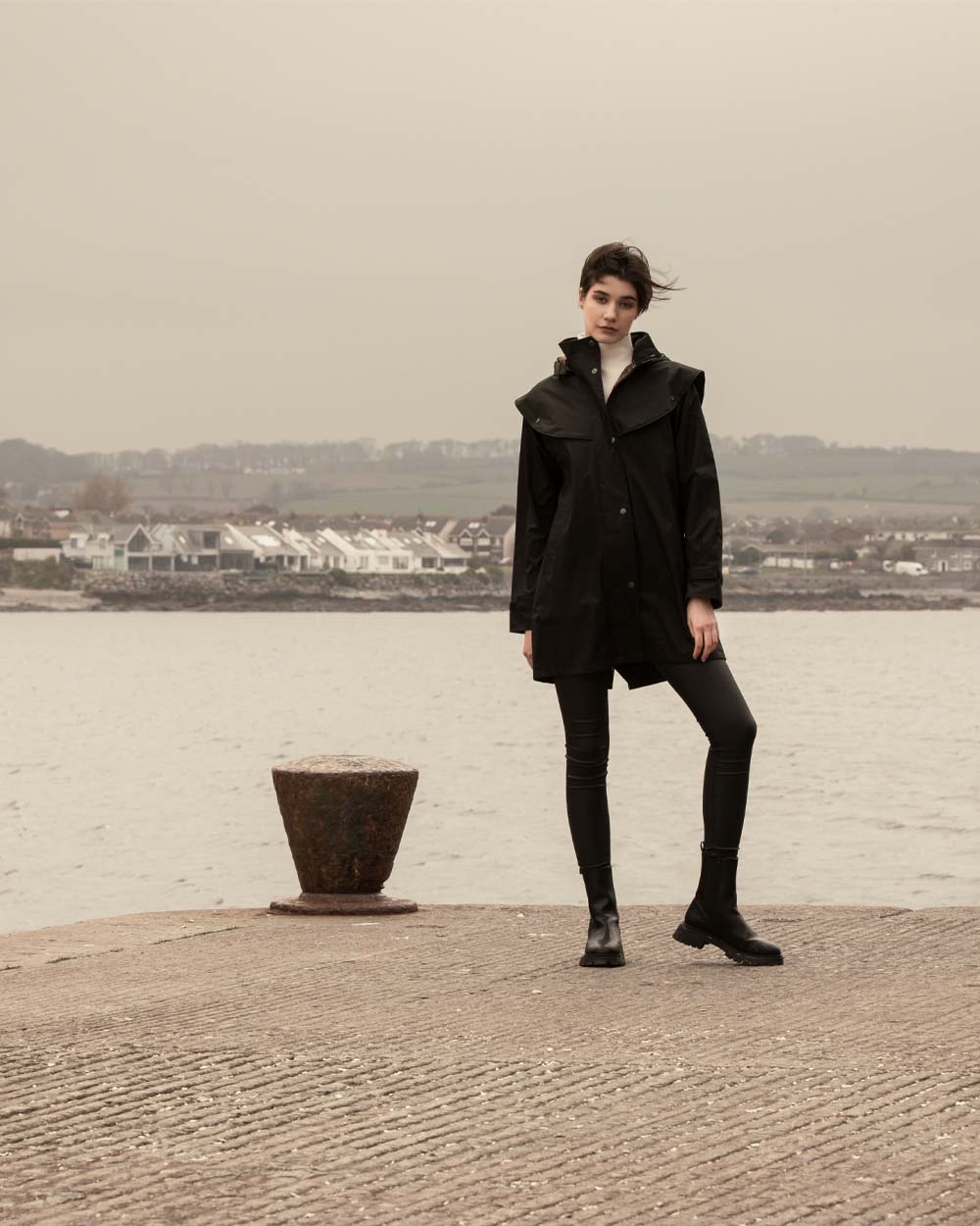 Black coloured Jack Murphy Cotswold Ladies Waterproof 3/4 Coat on Ocean background