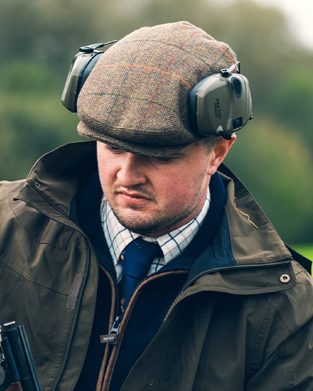 Tweed Brown Coloured Jack Pyke Wool Blend Tweed Flat Cap On A Blurry Background