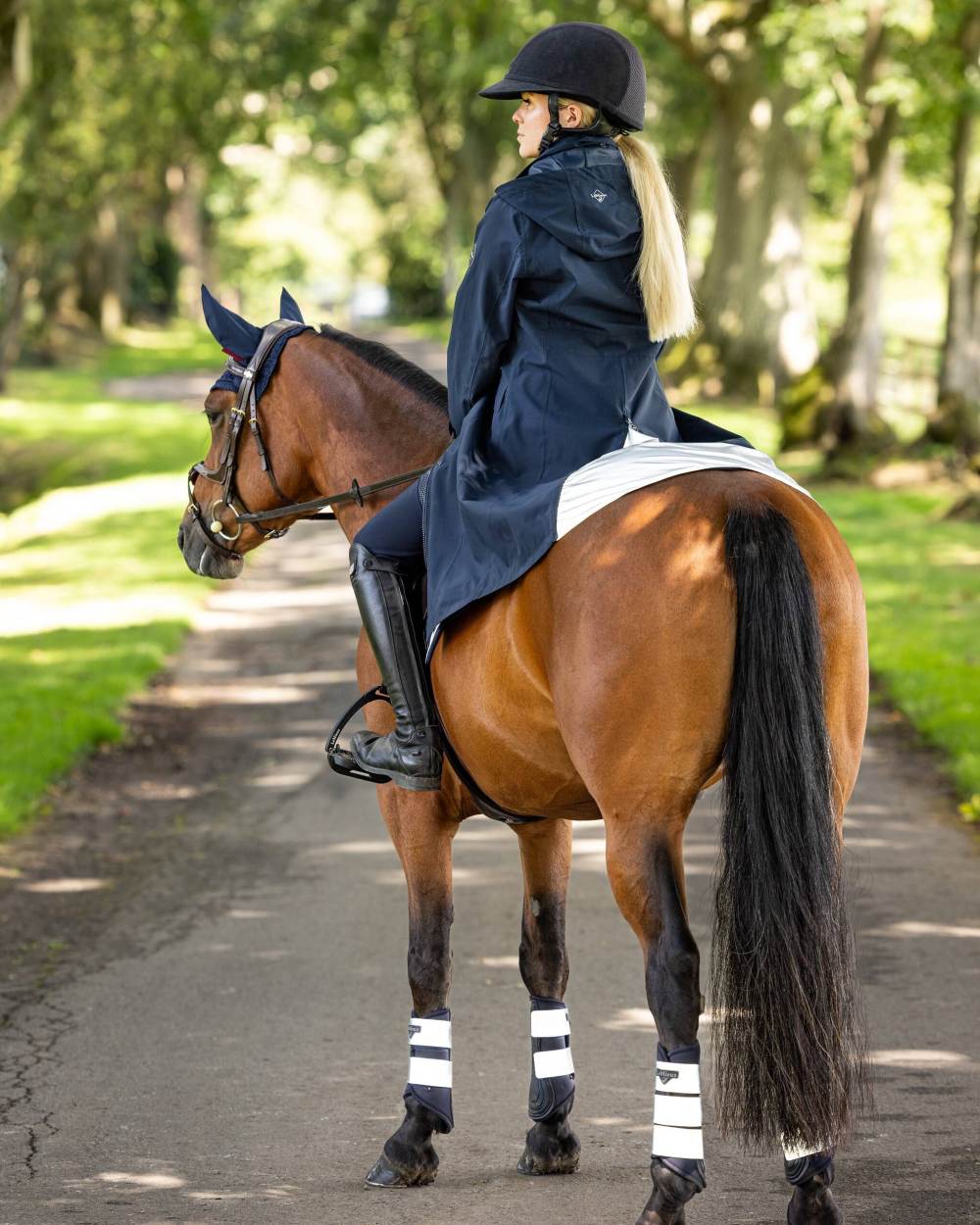 Navy coloured LeMieux Amelie Waterproof Lightweight Riding Coat on horse background 
