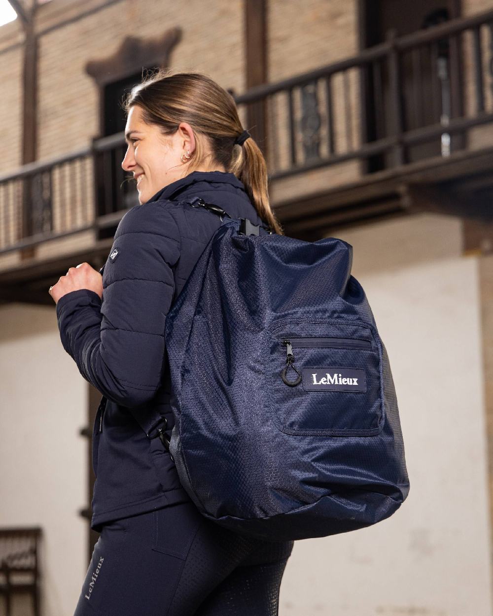 Navy coloured LeMieux Carry All Backpack with blurry building in background