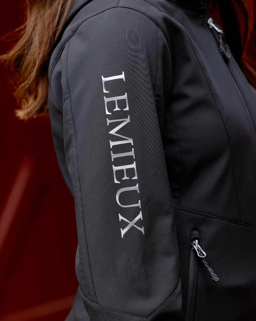 Black coloured LeMieux Celine Softshell Jacket on red background