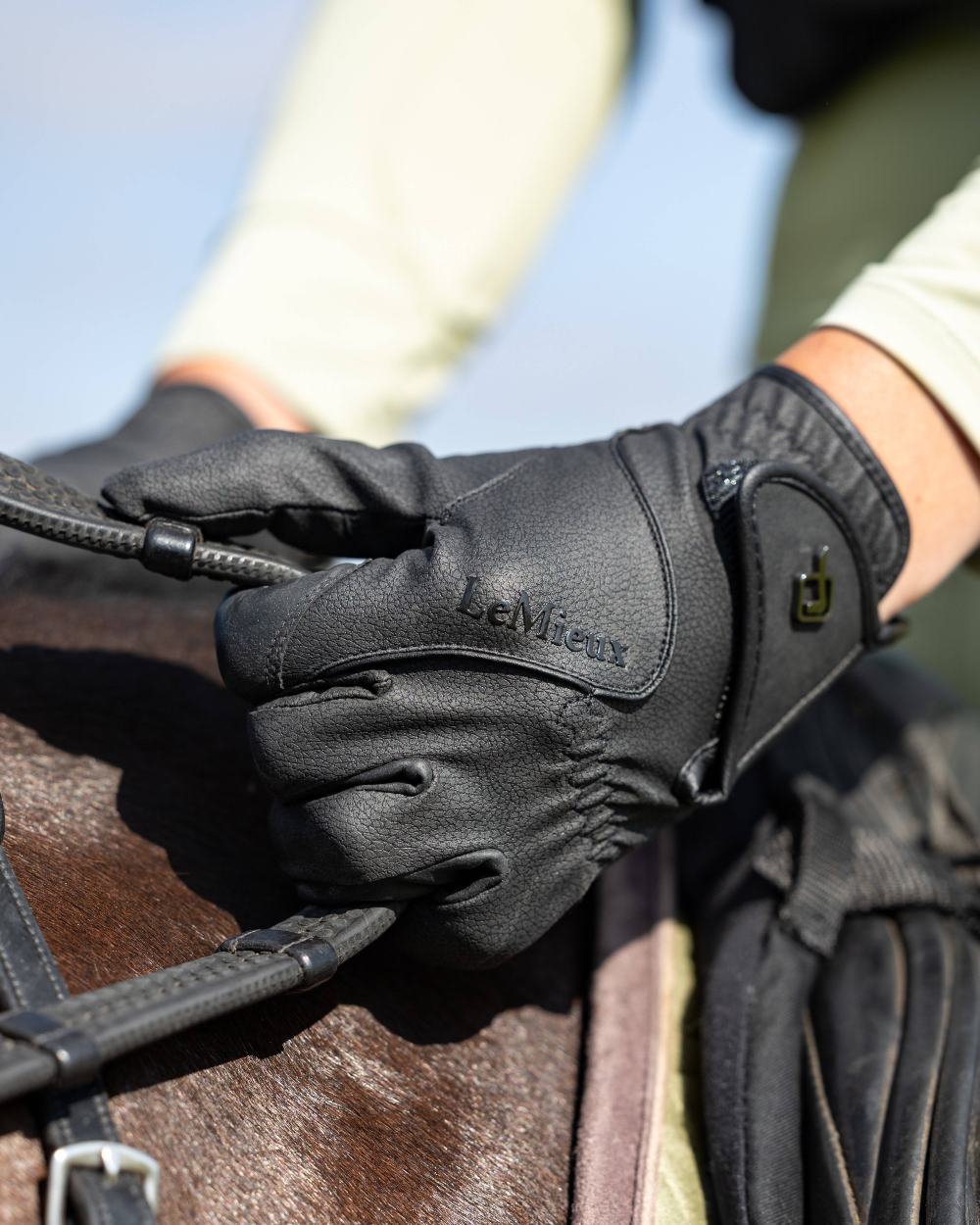 Black coloured LeMieux Close Contact Gloves on horse background
