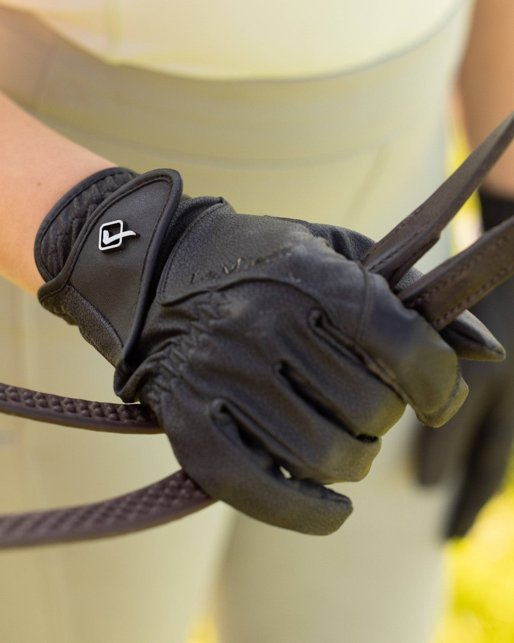 Black coloured LeMieux Close Contact Gloves on green background