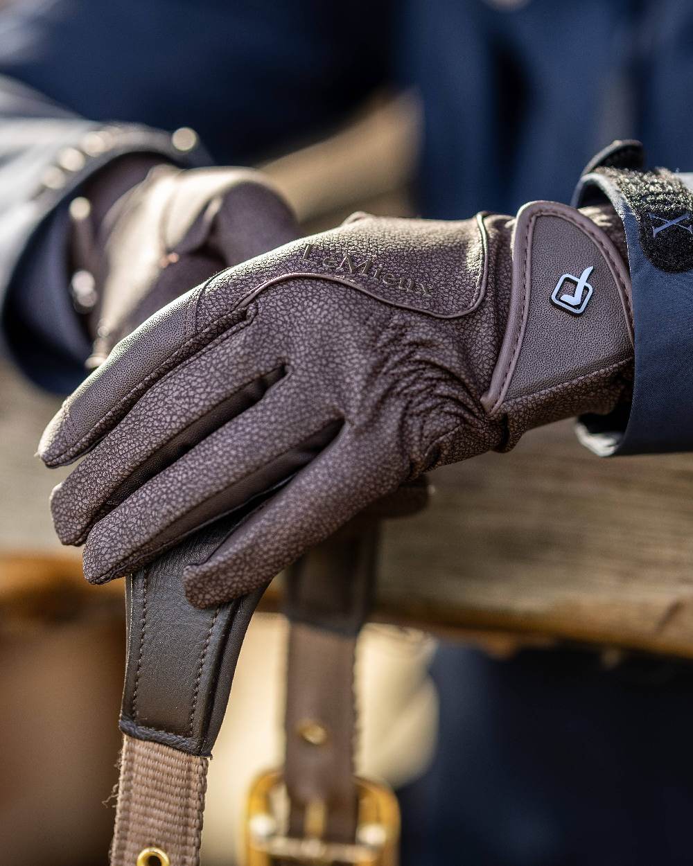 Brown coloured LeMieux Close Contact Gloves on fence background