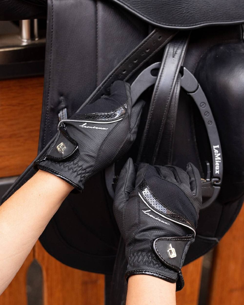 Black coloured LeMieux Competition Gloves with Saddle in background 
