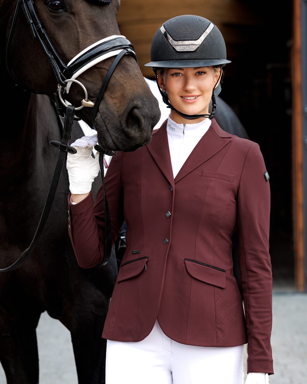 Burgundy coloured LeMieux Dynamique Show Jacket with horse in background
