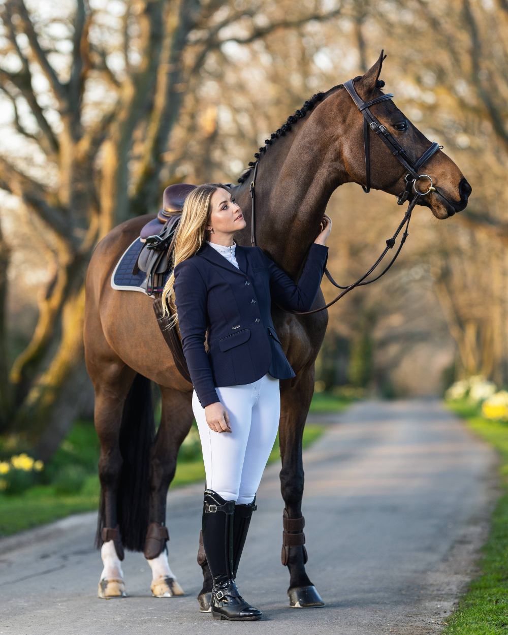 Navy coloured LeMieux Dynamique Show Jacket with horse in background
