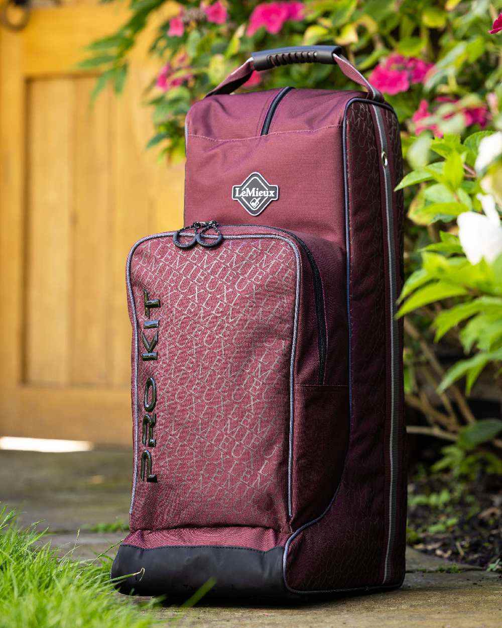 Burgundy coloured LeMieux Elite Pro Boot & Hat Bag on floral background