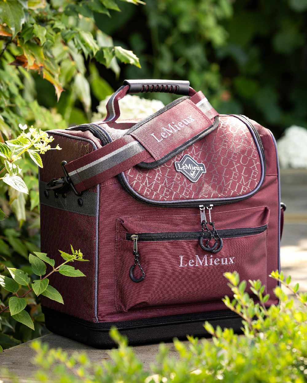 Burgundy coloured LeMieux Elite Pro Grooming Bag on garden background