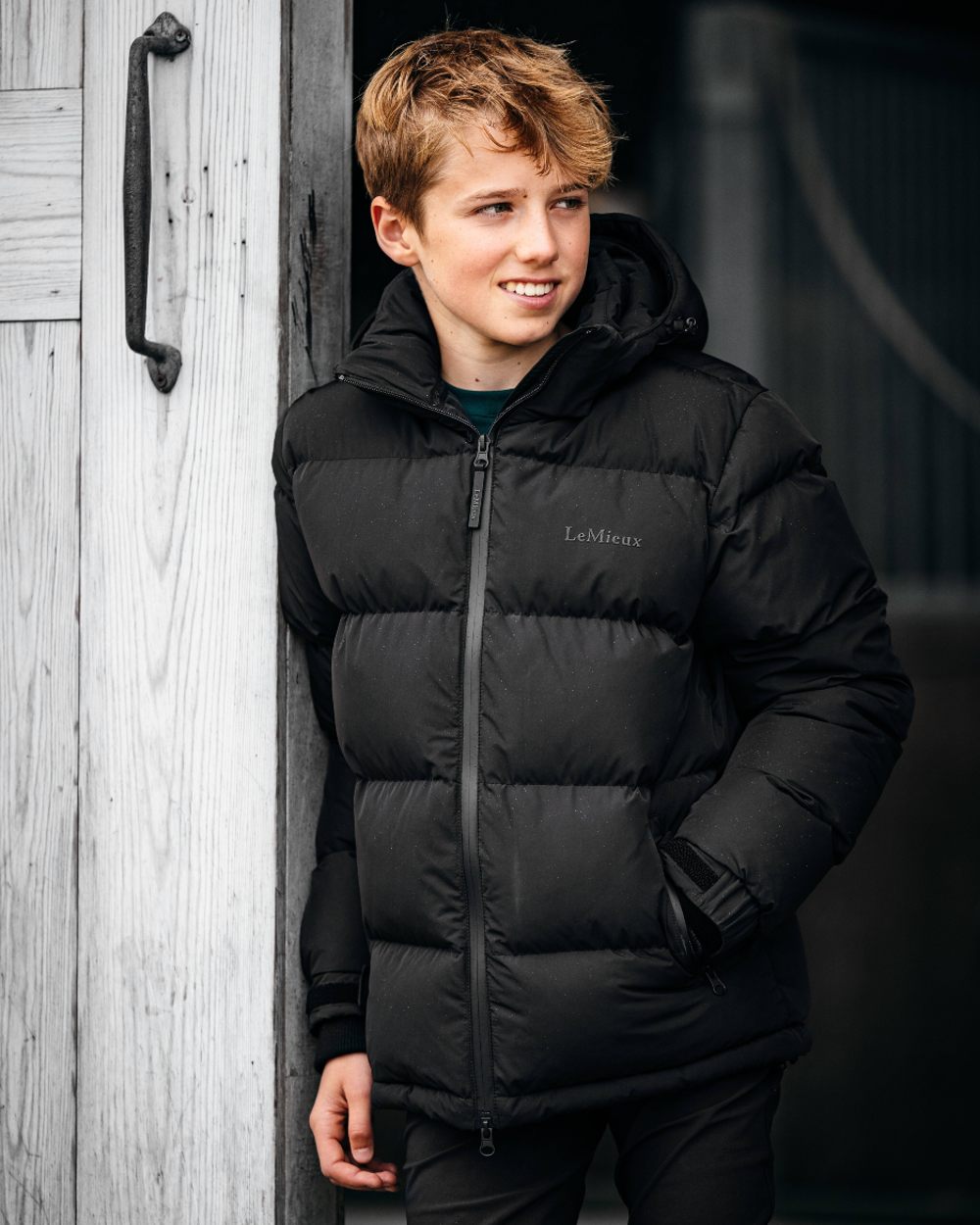 Black coloured LeMieux Elite Young Rider Boys Puffer Jacket on stable background 