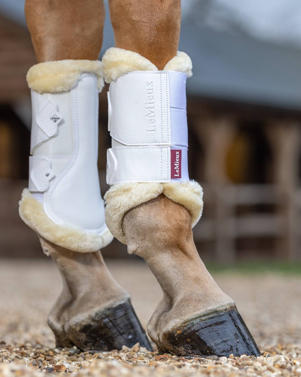 Natural/White coloured LeMieux Fleece Edged Mesh Brushing Boots on blurry stable background