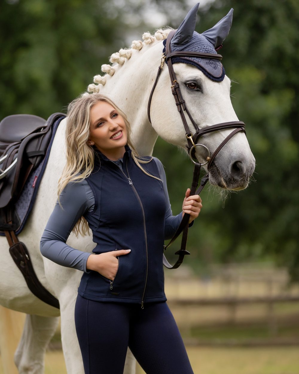 Navy coloured LeMieux Giselle Gilet with horse in background 