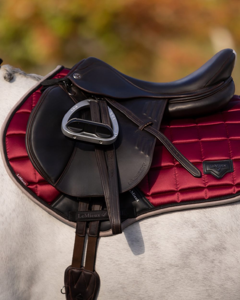 Ember Coloured LeMieux Loire Classic Close Contact Square On A Outer Yard Background