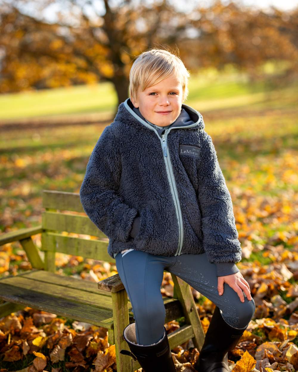 Petrol Coloured LeMieux Mini Teagan Fleece Jacket On A Outer Yard Background