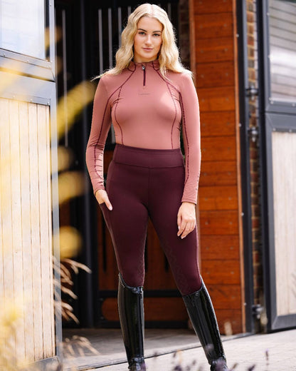 Merlot coloured LeMieux Naomi Pull On Breeches with stable in background 