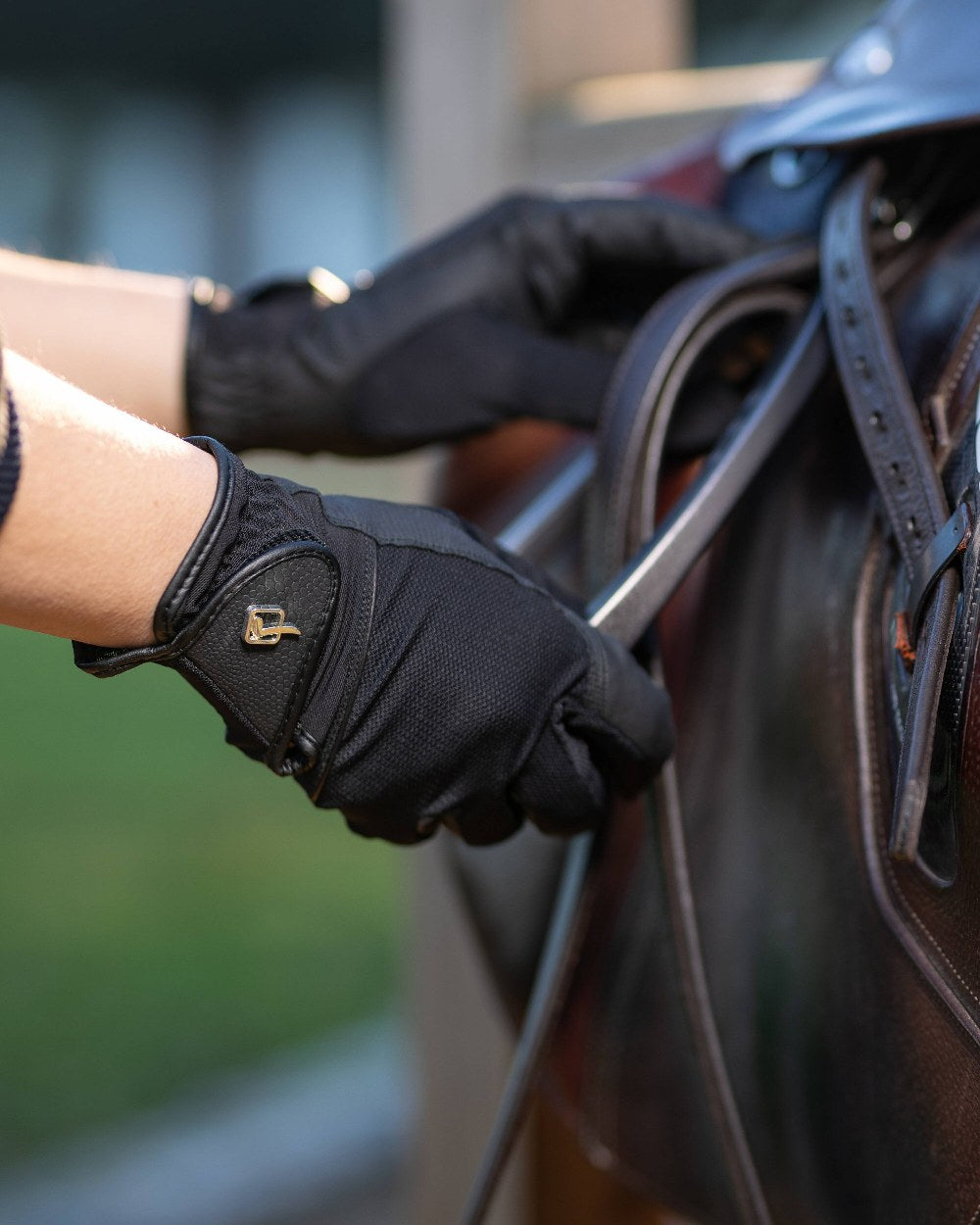 Black coloured LeMieux Pro Mesh Gloves with horse in background