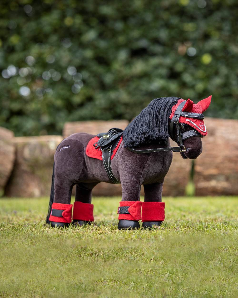 Chilli coloured LeMieux Toy Pony Fly Hood on blurry green background