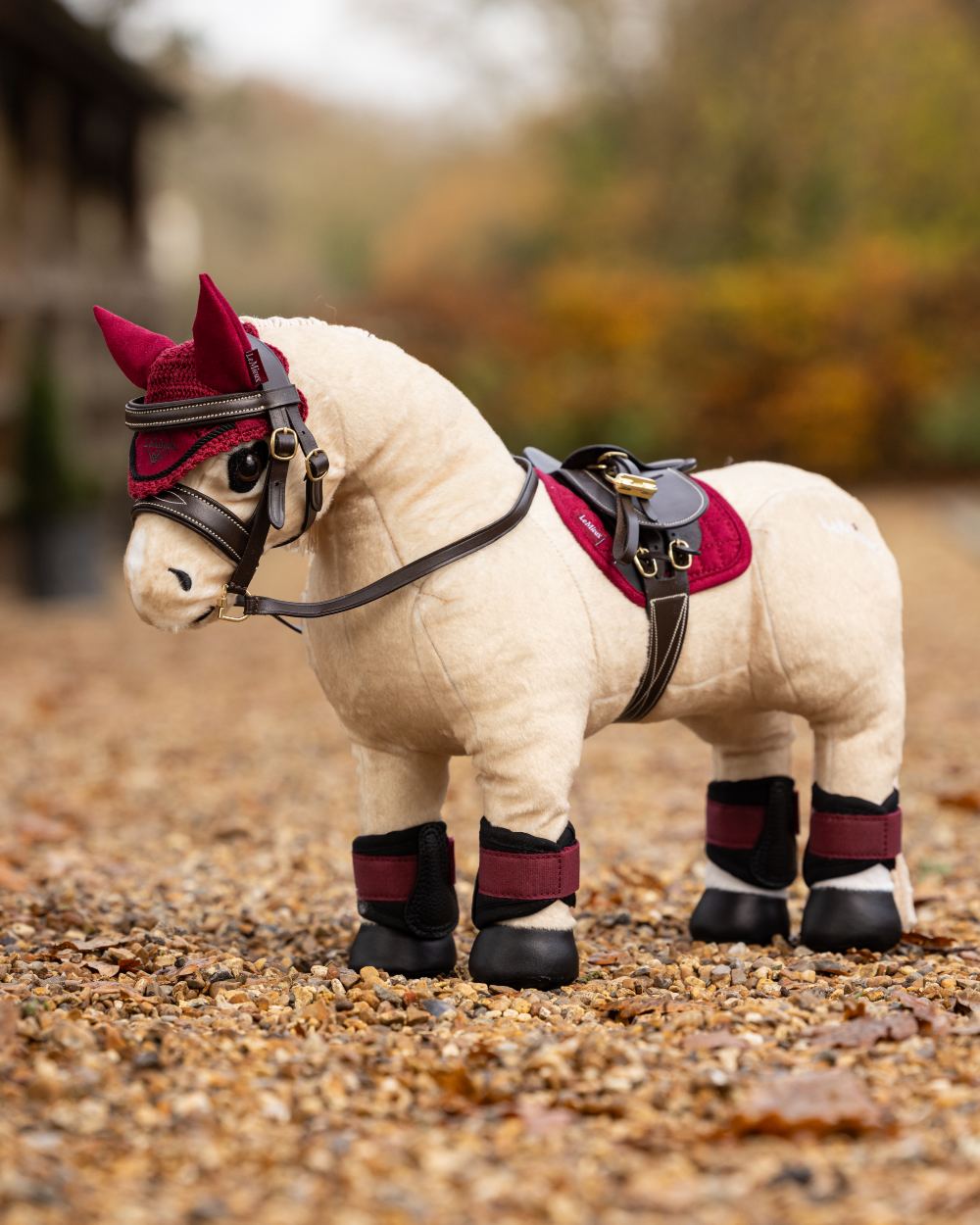Ember Coloured LeMieux Toy Pony Pad On A Yard Background