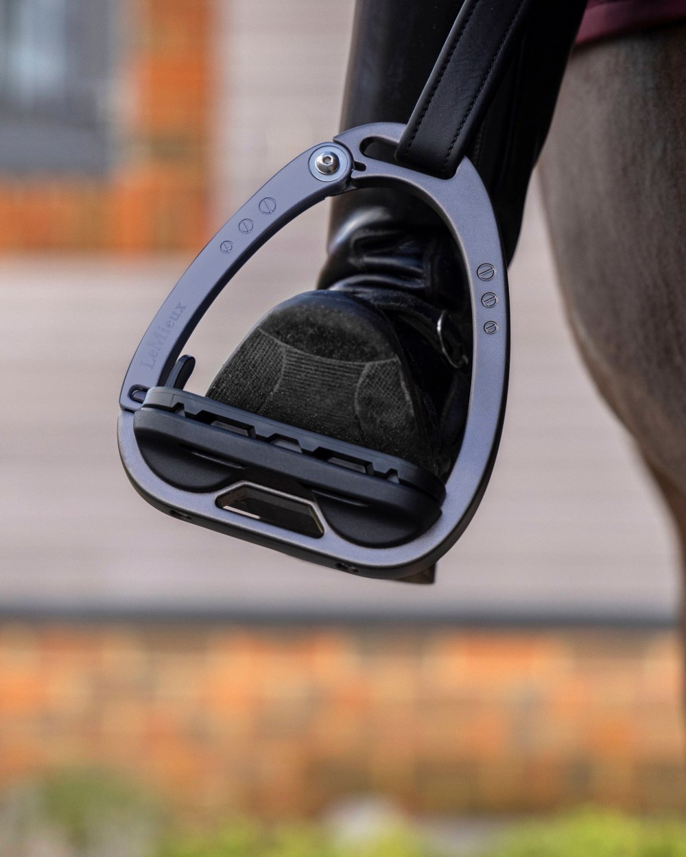 Carbon coloured LeMieux Vector Balance Stirrup on blurry background
