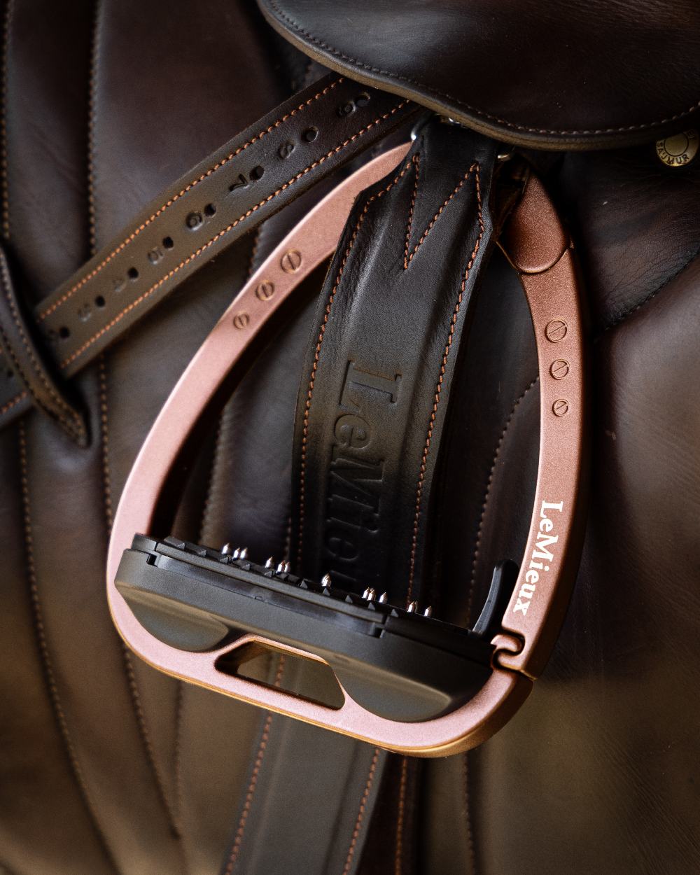 Rose Gold coloured LeMieux Vector Balance Stirrup on brown background