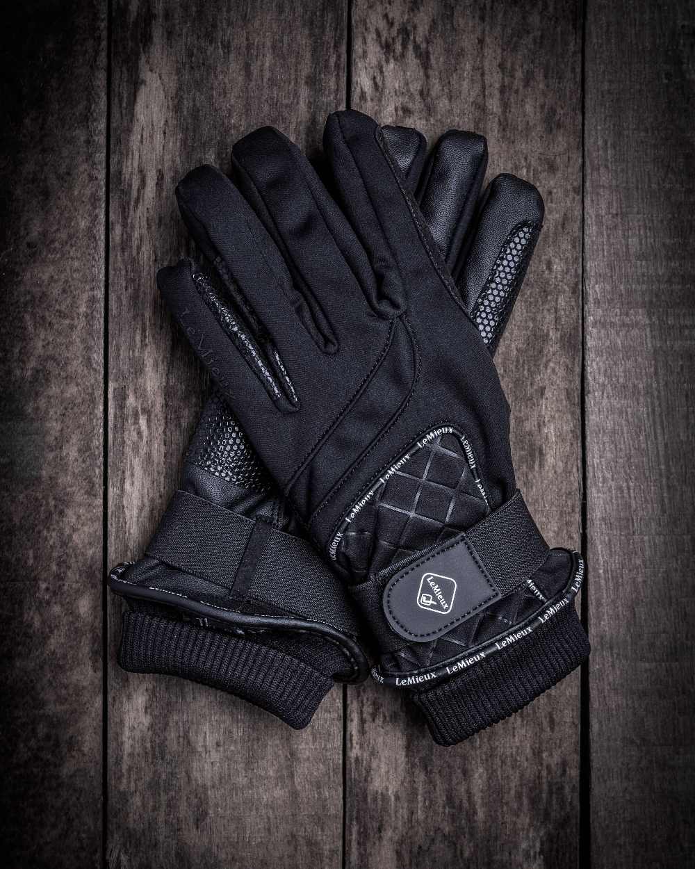 Black coloured LeMieux Waterproof Lite Gloves on wooden background