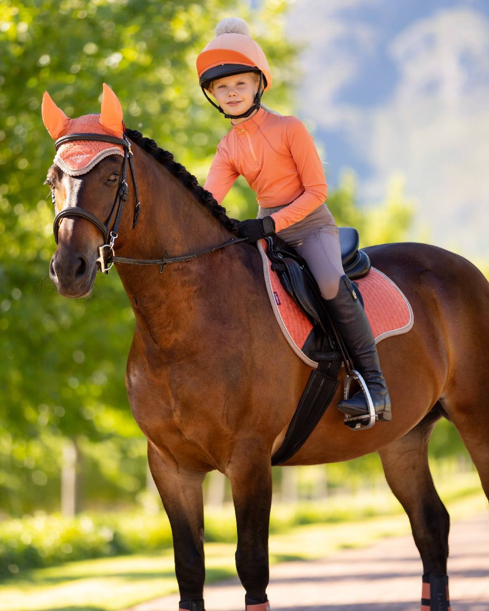 Apricot coloured LeMieux Young Rider Base Layer on blurry green background
