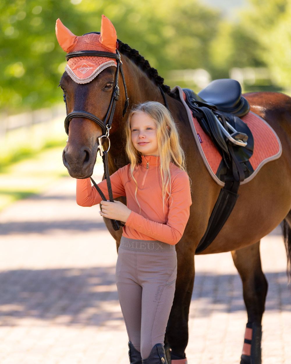 Apricot coloured LeMieux Young Rider Base Layer on blurry green background