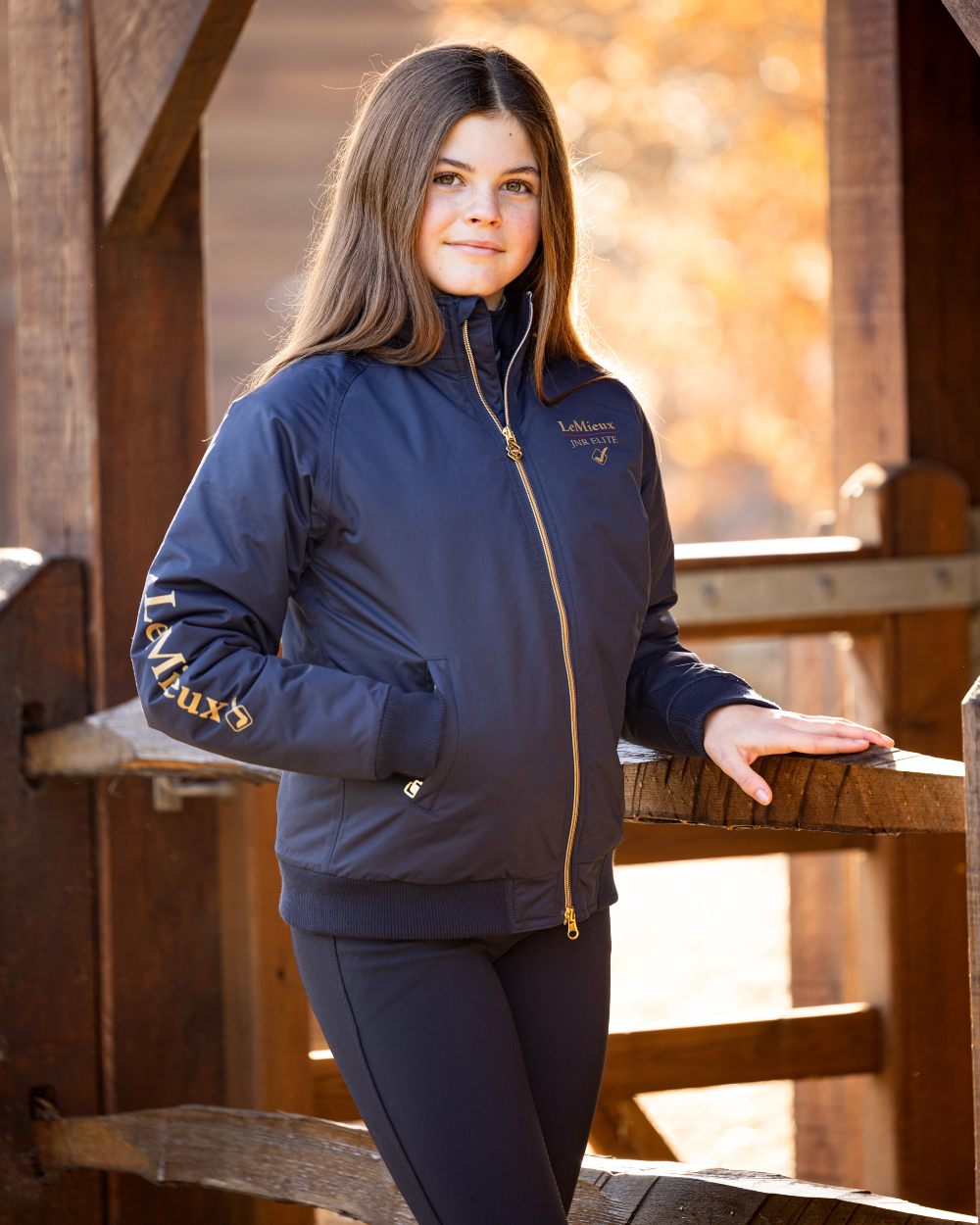Navy coloured LeMieux Young Rider Elite Team Jacket with shed in background 