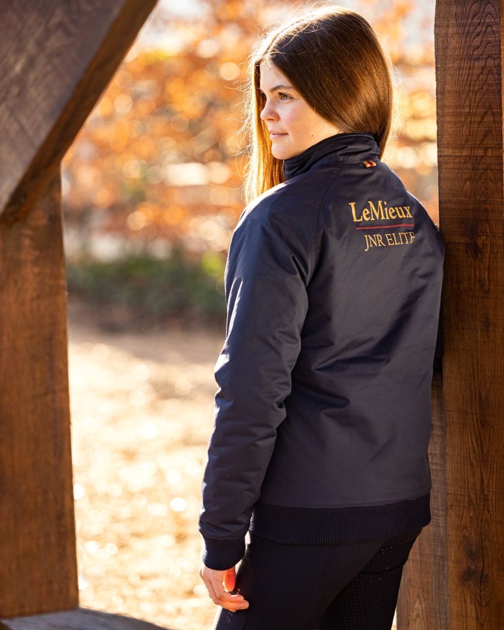 Navy coloured LeMieux Young Rider Elite Team Jacket with shed in background 