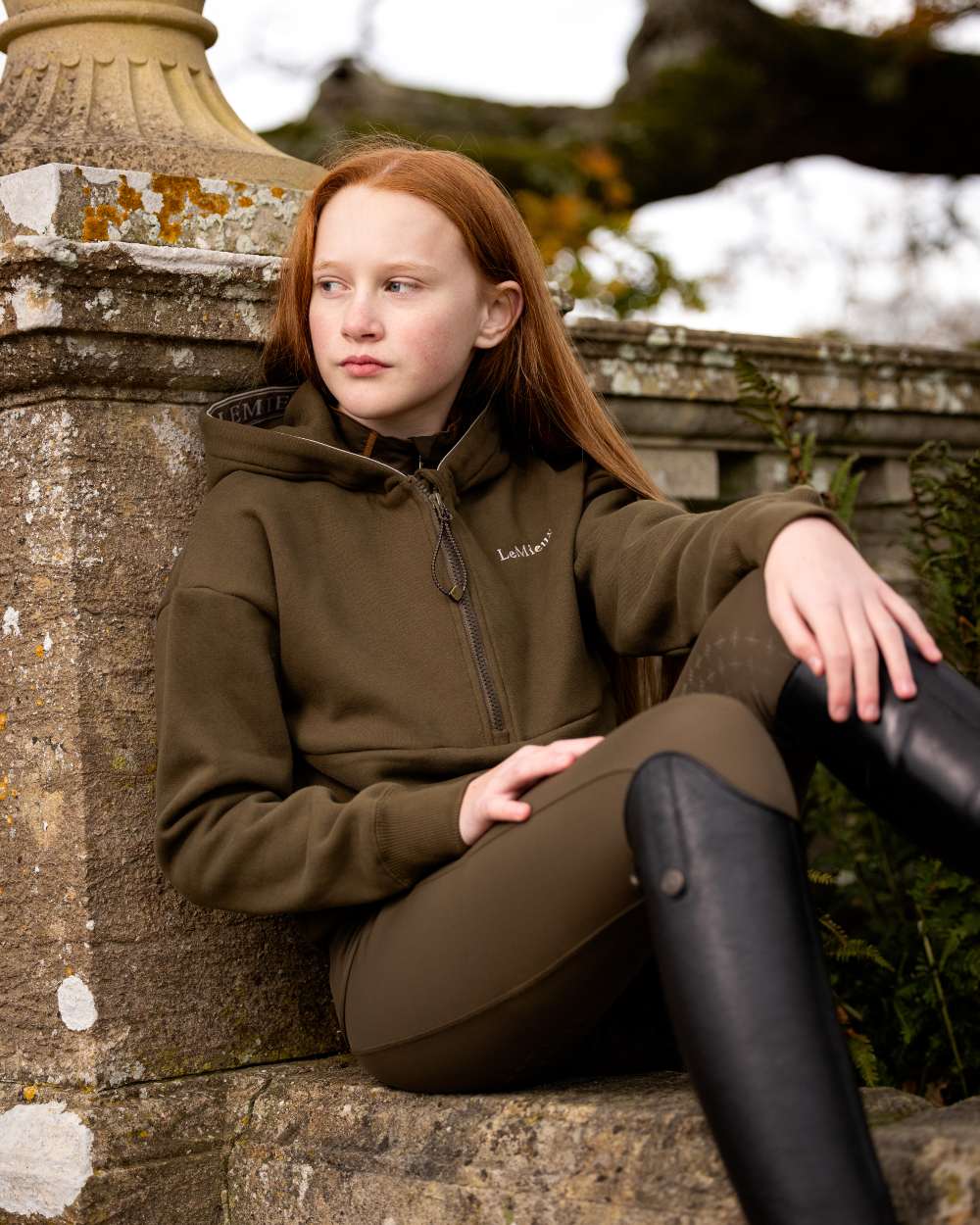 Alpine Coloured LeMieux Young Rider Hettie Half Zip Hoodie On A Outer Yard Background